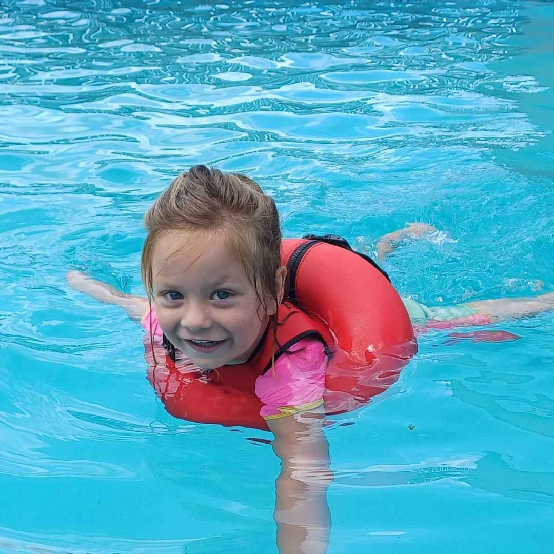 Girl swimming confidently in turquoise pool